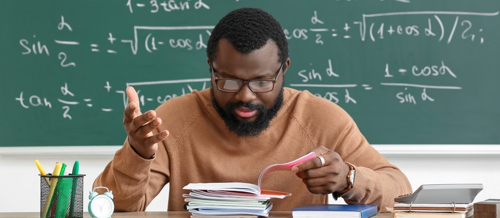 Displeased,African american,Teacher,Checking,Homework,In,Classroom